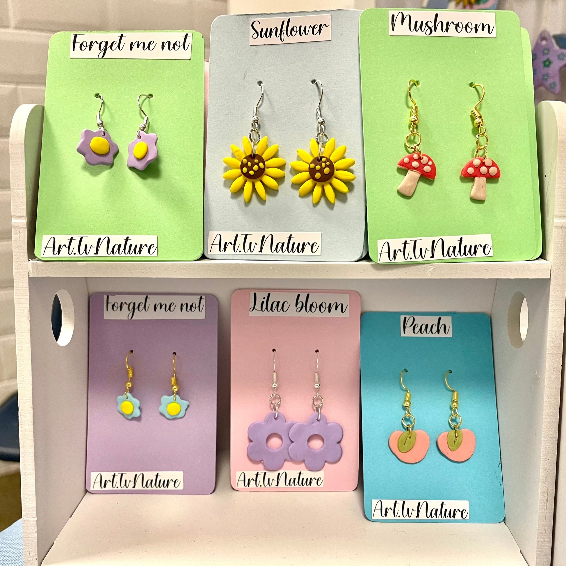 lilac bloom flower shaped earrings on a display stand with other earring designs