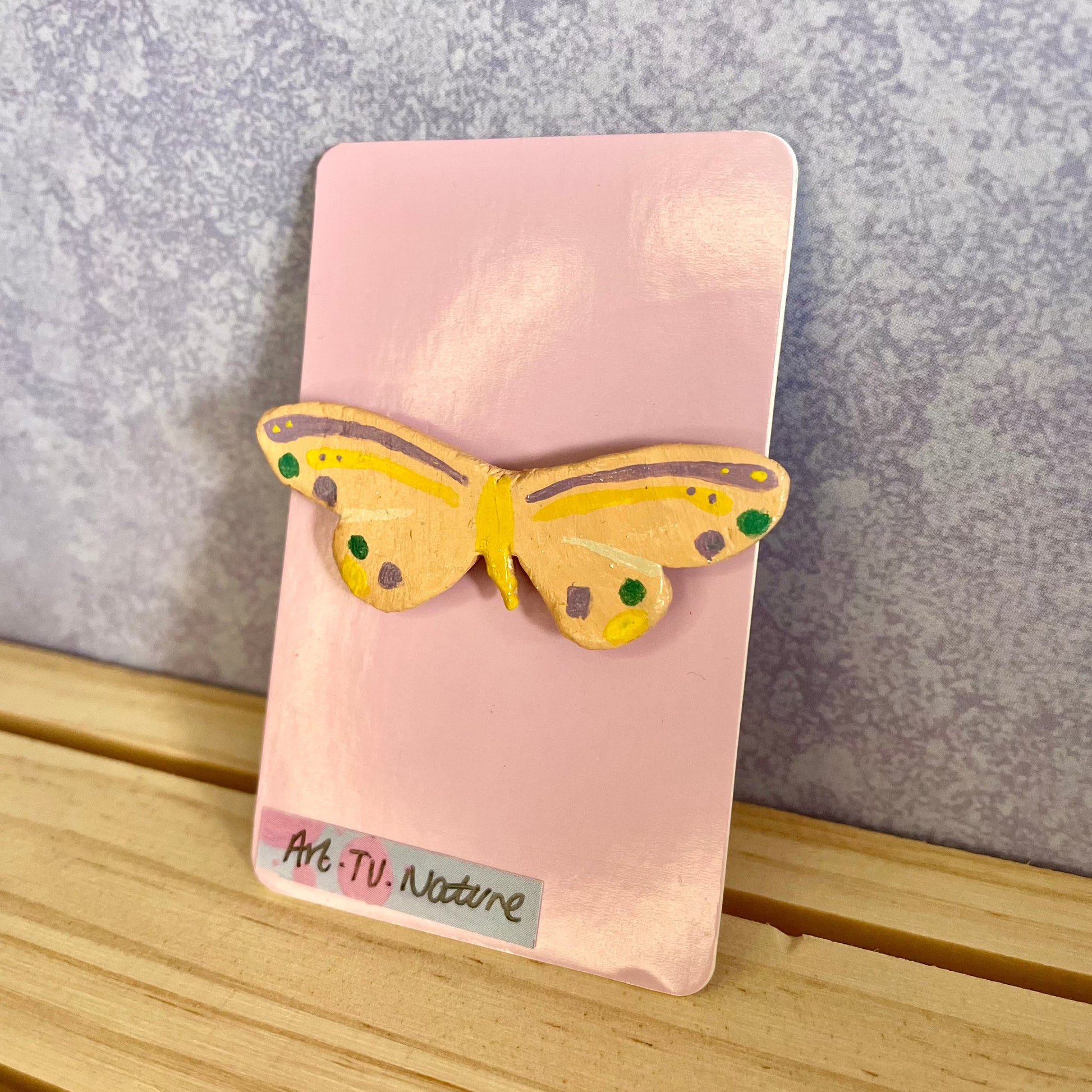 clay butterfly pin , on pink backing card 